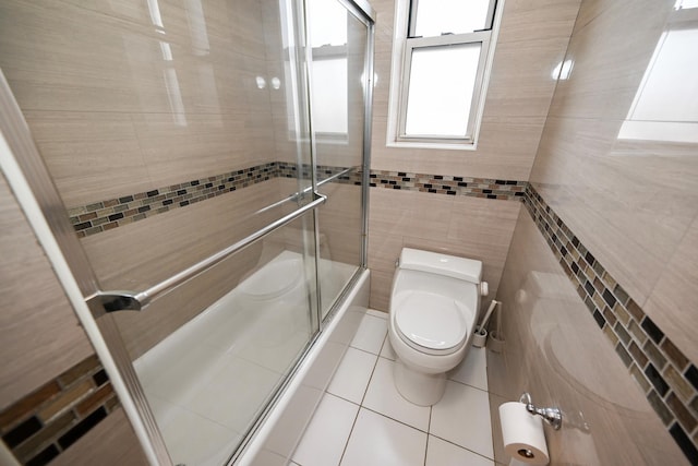 bathroom with toilet, tile walls, and tile patterned floors