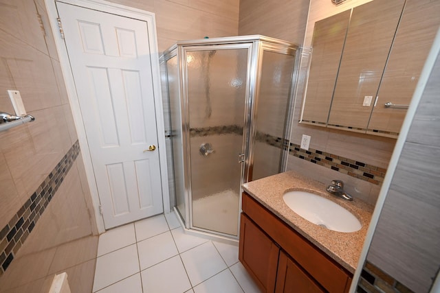 bathroom with tile walls, tile patterned floors, vanity, a shower stall, and backsplash