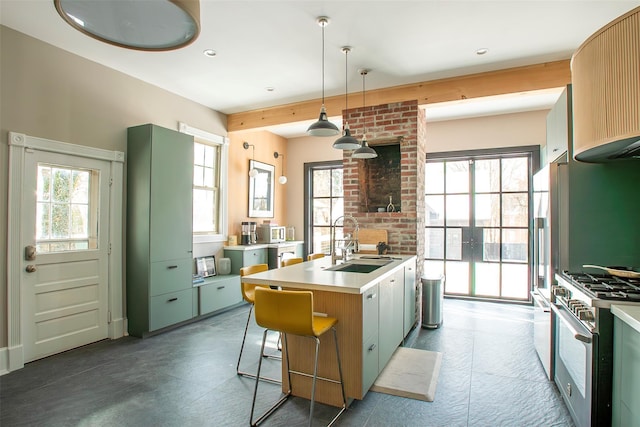 kitchen with an island with sink, ventilation hood, light countertops, a sink, and high end stainless steel range oven