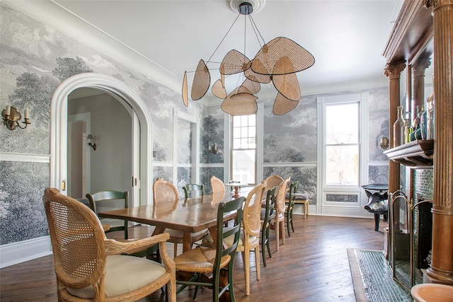 dining space with baseboards, arched walkways, hardwood / wood-style flooring, and wallpapered walls