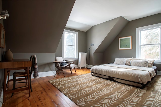 bedroom featuring wood-type flooring, baseboards, radiator, and vaulted ceiling