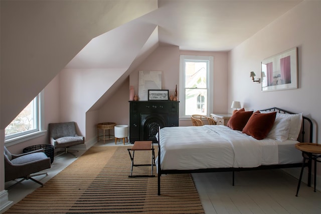 bedroom with wood finished floors, multiple windows, and vaulted ceiling