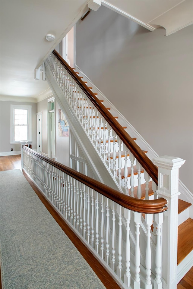 stairway with ornamental molding, baseboards, and wood finished floors