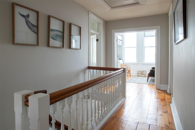 corridor featuring an upstairs landing, light wood-style flooring, and baseboards