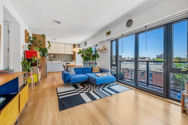 living room with light wood-style floors, visible vents, and a city view