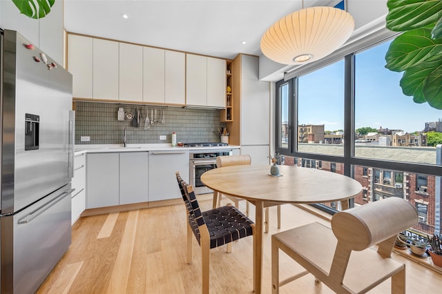 kitchen with light wood finished floors, white cabinetry, stainless steel appliances, and light countertops