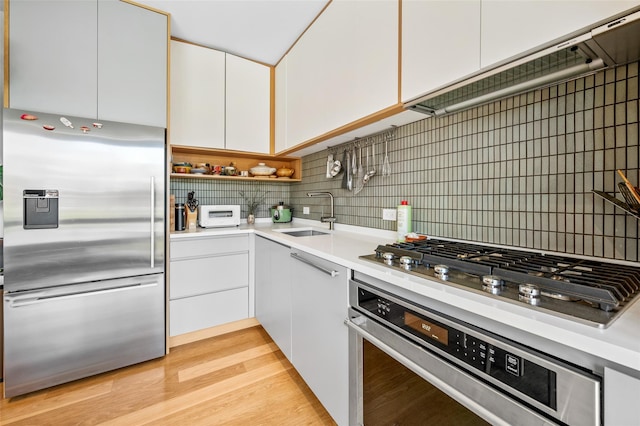 kitchen with stainless steel appliances, light countertops, a sink, and white cabinetry