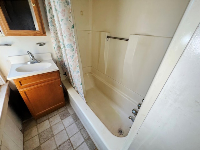 full bathroom with stone tile floors, shower / bath combo with shower curtain, and vanity