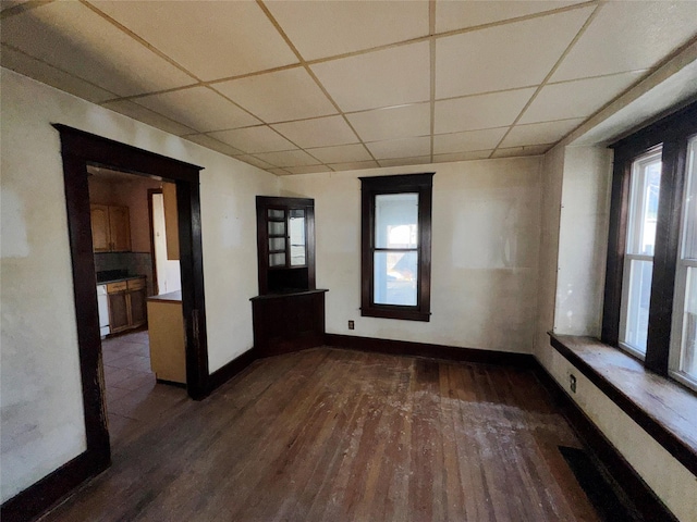 spare room with dark wood-style floors, baseboards, and a drop ceiling