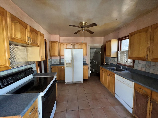 kitchen featuring white appliances, dark tile patterned floors, backsplash, and a sink