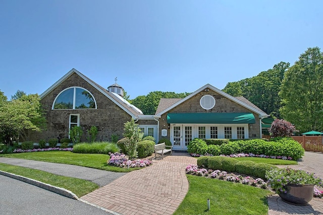 view of front of property with french doors, fence, and a front lawn