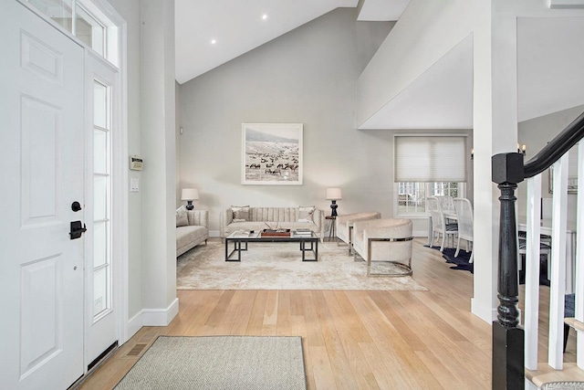 entryway featuring stairs, high vaulted ceiling, baseboards, and light wood-style floors