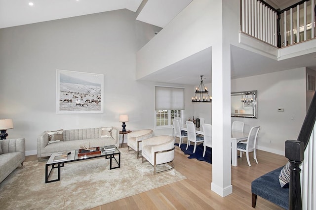 living area with baseboards, a high ceiling, a chandelier, and wood finished floors