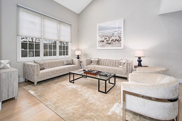 living room with high vaulted ceiling, baseboards, and wood finished floors