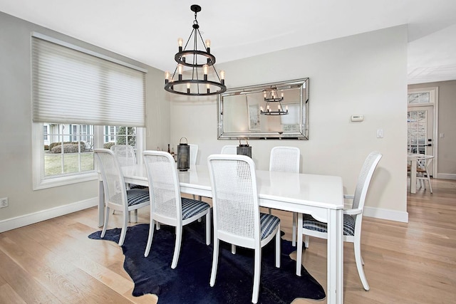 dining space with light wood-style flooring, baseboards, and an inviting chandelier