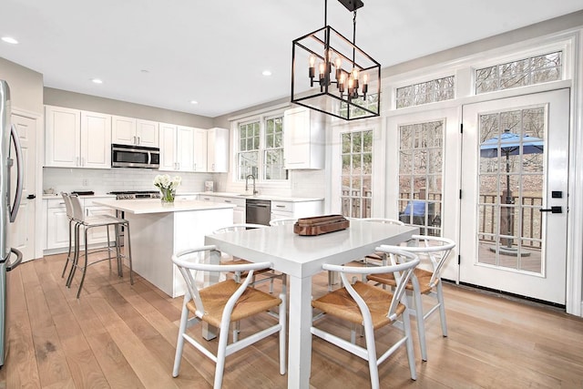 kitchen featuring light wood-style flooring, white cabinets, appliances with stainless steel finishes, backsplash, and a center island