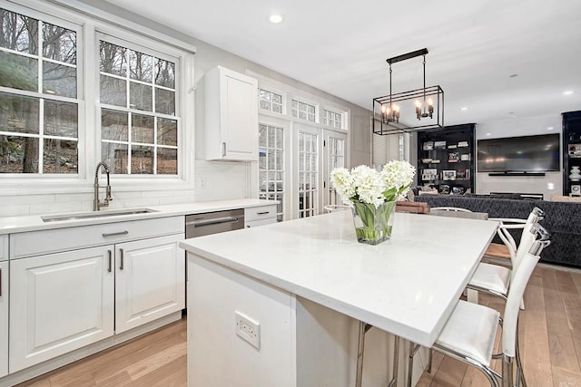 kitchen with light countertops, light wood finished floors, a sink, and white cabinetry