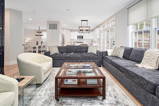 living area with a chandelier, light wood-style flooring, visible vents, and recessed lighting