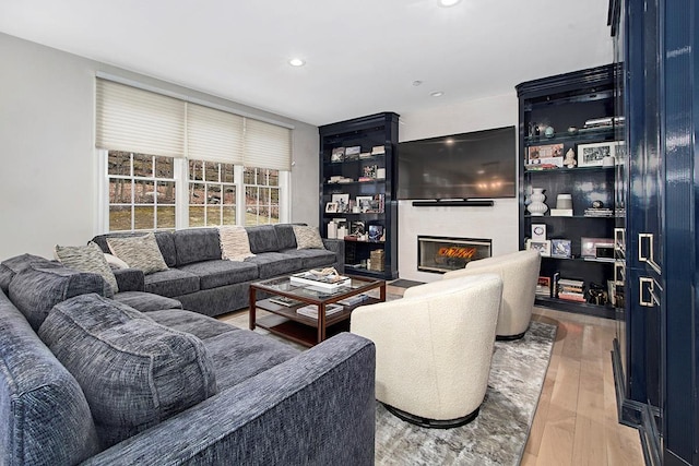 living room with wood finished floors, a glass covered fireplace, and recessed lighting