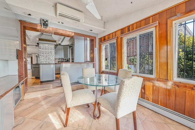 dining room featuring a baseboard heating unit, wood walls, and a wall mounted AC