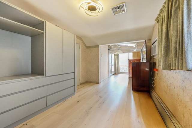 hallway with a baseboard radiator, visible vents, and light wood-style floors