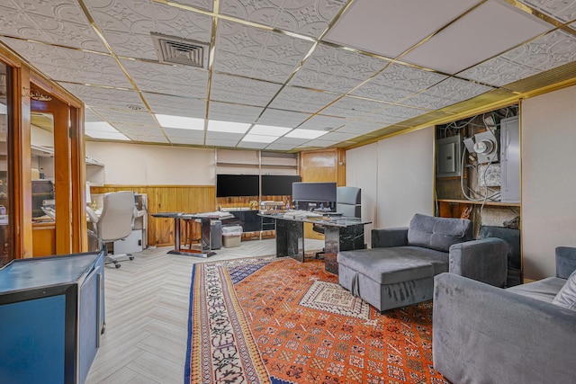 living room with electric panel, visible vents, wainscoting, a paneled ceiling, and wood walls