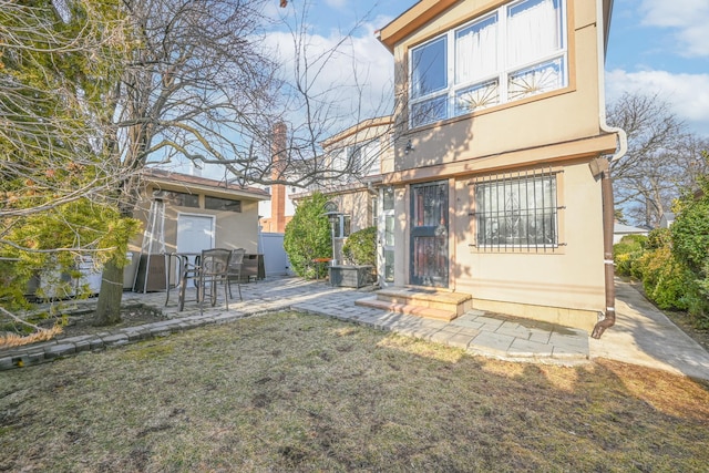 back of property with a yard, a patio area, and stucco siding