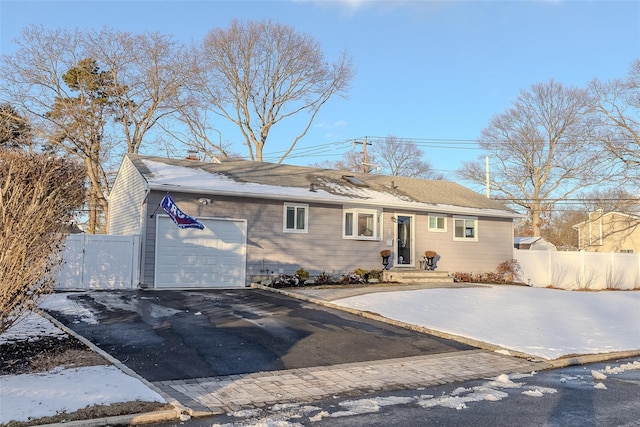 ranch-style home featuring driveway, an attached garage, and fence