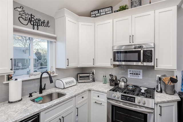 kitchen with appliances with stainless steel finishes, white cabinets, and a sink