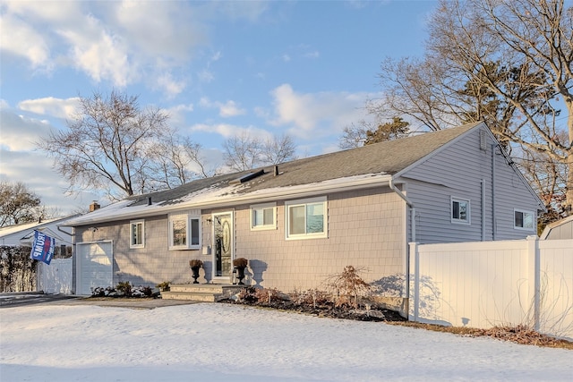 back of property with an attached garage and fence