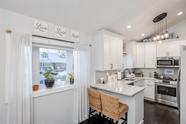 kitchen featuring white cabinets, decorative backsplash, lofted ceiling, light stone countertops, and stainless steel appliances