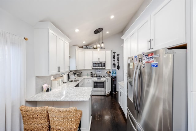 kitchen with white cabinets, dark wood-style flooring, a peninsula, vaulted ceiling, and stainless steel appliances