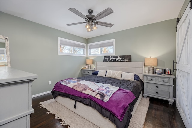 bedroom featuring dark wood-style flooring, ceiling fan, baseboards, and a barn door