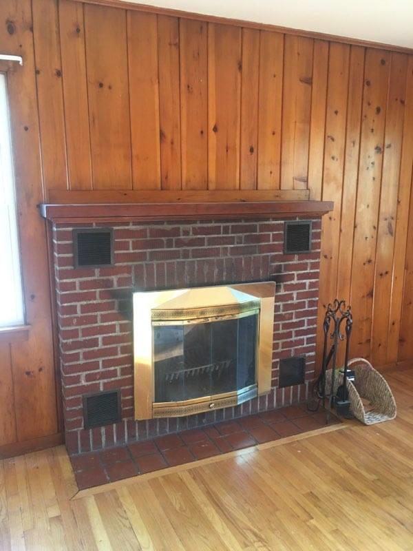 interior details with a brick fireplace, wood finished floors, and visible vents