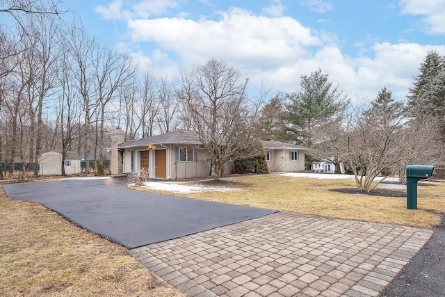 view of front of home featuring driveway, a front lawn, and a chimney