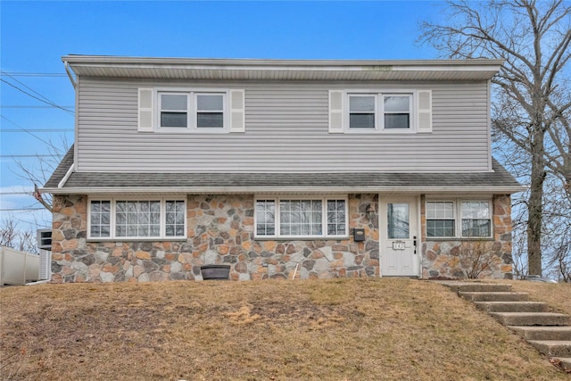 view of front of property featuring stone siding, a front lawn, and a shingled roof