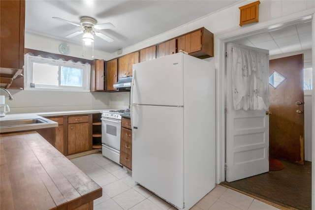 kitchen with under cabinet range hood, white appliances, brown cabinets, and a sink