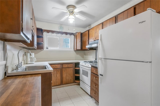 kitchen with under cabinet range hood, white appliances, brown cabinetry, and a sink