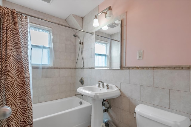 full bathroom featuring a sink, shower / bathtub combination with curtain, toilet, and tile walls