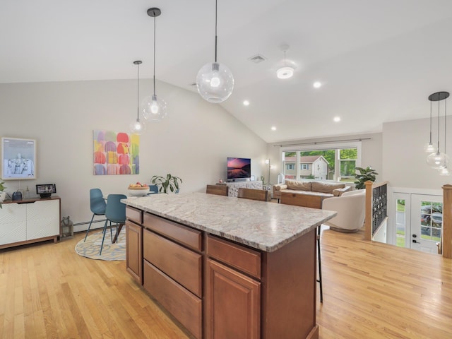 kitchen featuring open floor plan, visible vents, a kitchen island, and light wood finished floors