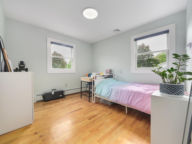 bedroom featuring light wood-type flooring, visible vents, and baseboard heating