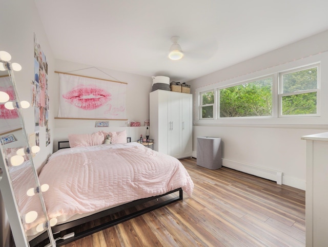 bedroom with baseboards, ceiling fan, light wood finished floors, and baseboard heating