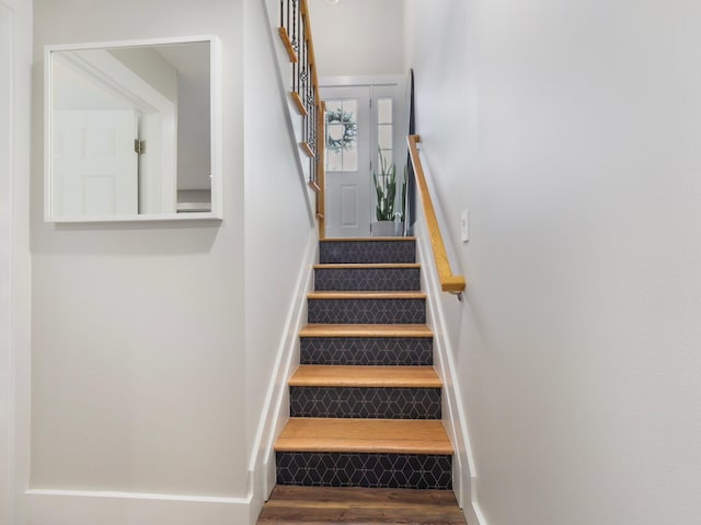 stairway with wood finished floors and baseboards