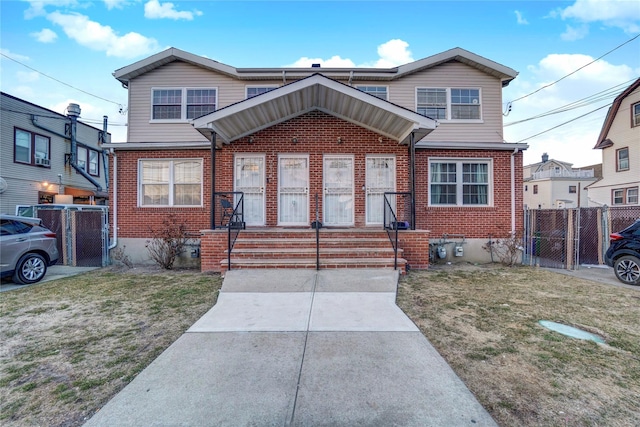 view of front of house with a gate, fence, a front lawn, and brick siding