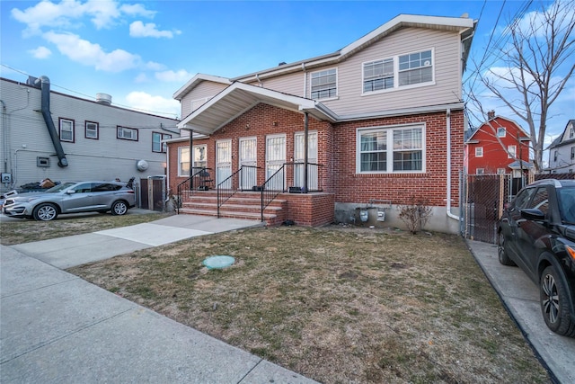 traditional home featuring a front yard, fence, and brick siding