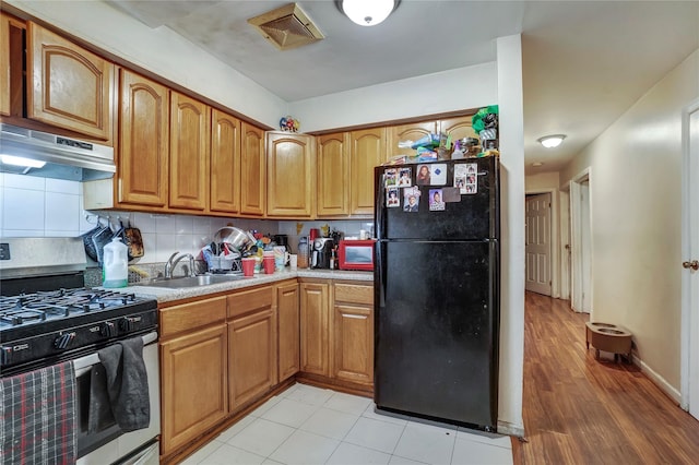 kitchen with light countertops, visible vents, freestanding refrigerator, under cabinet range hood, and stainless steel gas range oven