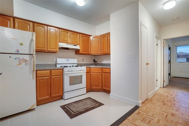 kitchen featuring under cabinet range hood, white appliances, a sink, baseboards, and brown cabinetry