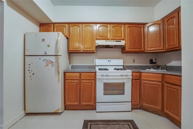 kitchen featuring white appliances, light tile patterned floors, dark countertops, under cabinet range hood, and a sink