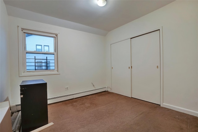 unfurnished bedroom with a baseboard heating unit, a closet, and carpet floors