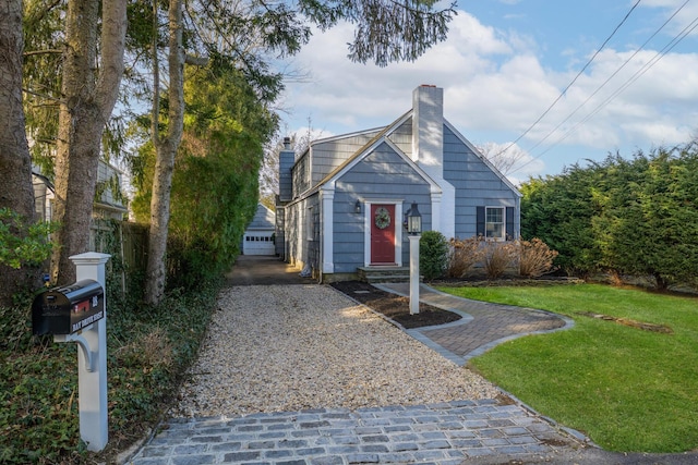 view of front of home featuring a front yard, an outdoor structure, and a chimney